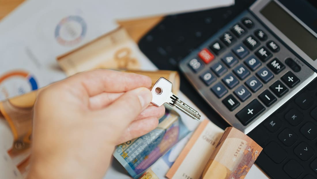 Money, a calculator and a key on real estate closing documents