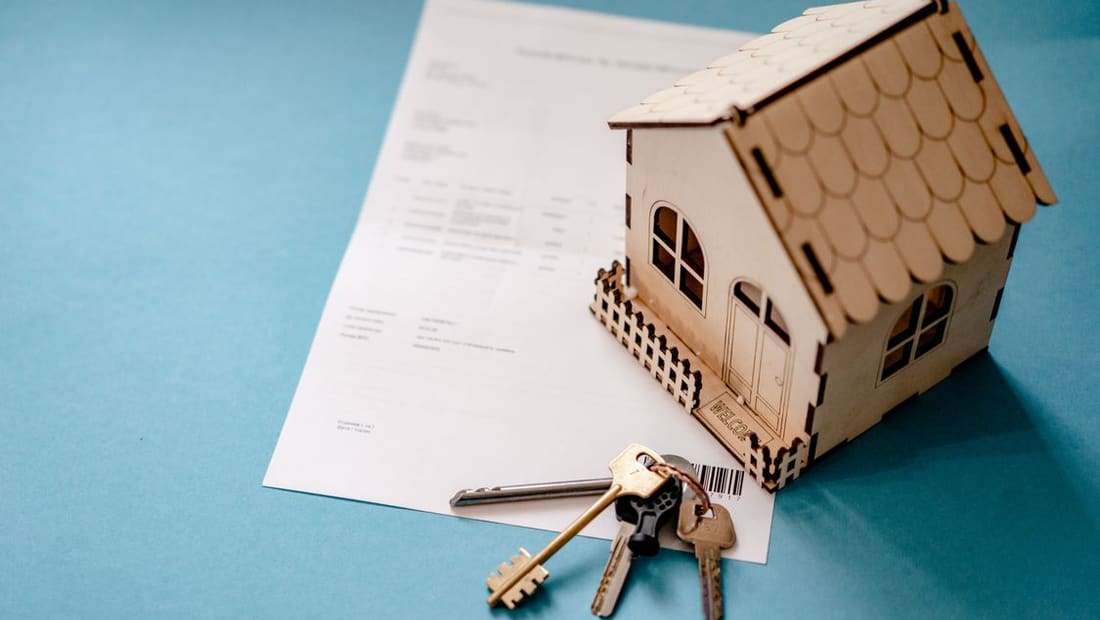 A model house on financial paperwork with house keys