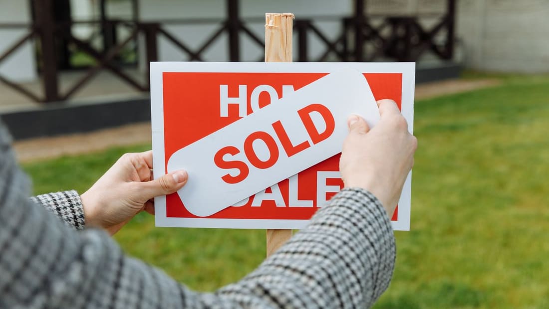 A red SOLD sign in front of a home