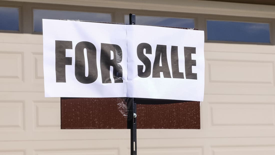 A real estate For Sale sign in front of a house