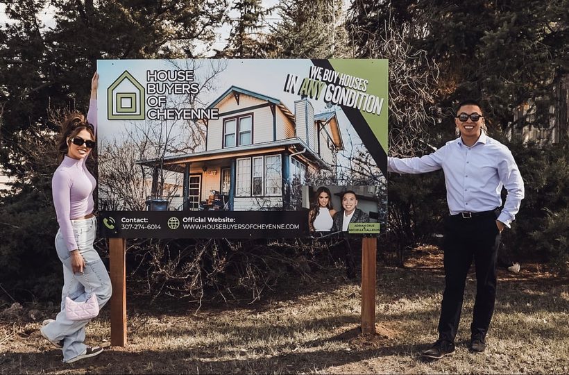 Adrian Cruz and Michelle Gallegos with the House Buyers of Cheyenne We Buy Houses sign